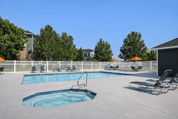 A swimming pool with a diving board and lounge chairs.